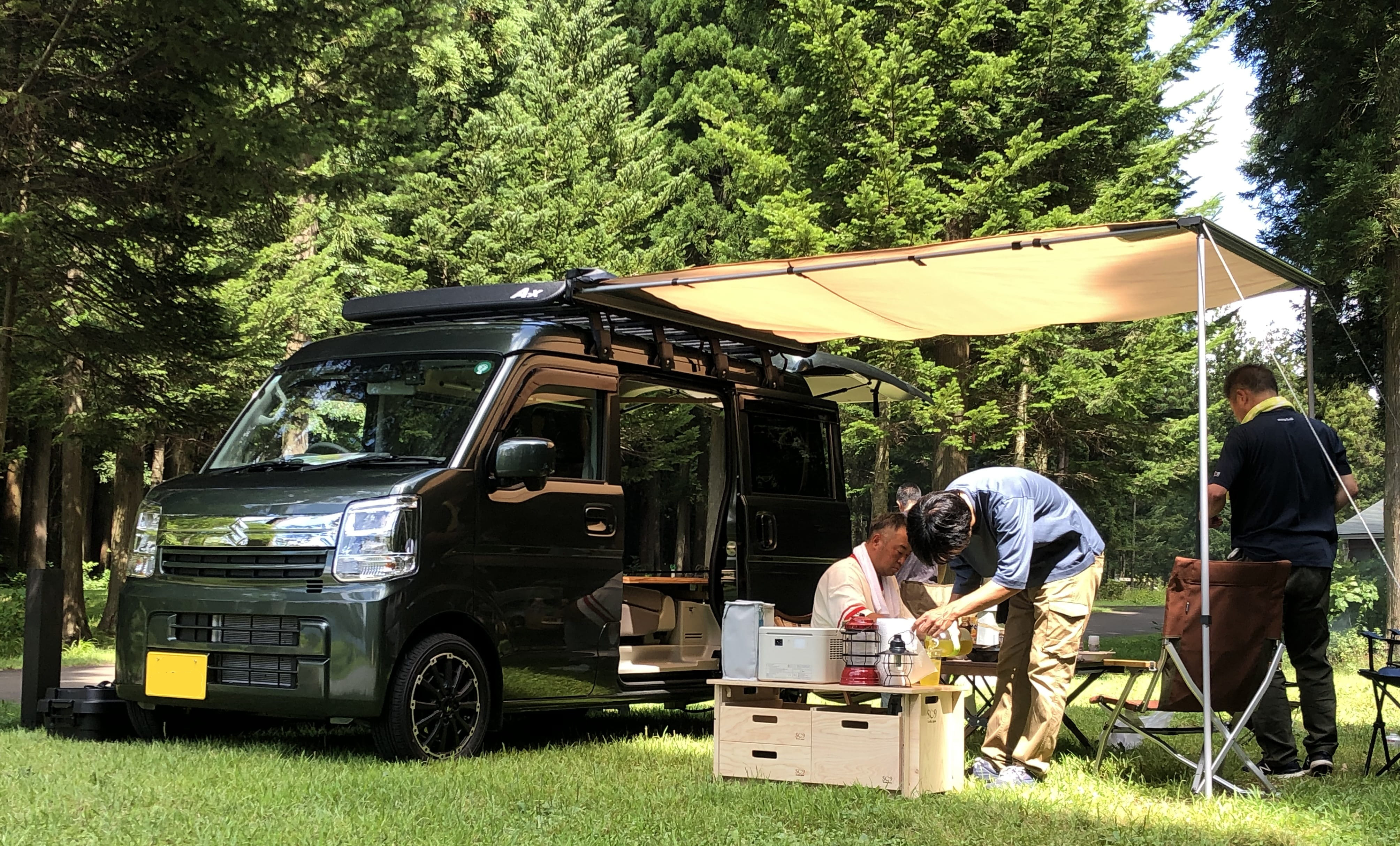 男性たちが車のそばでキャンプの準備をしている画像